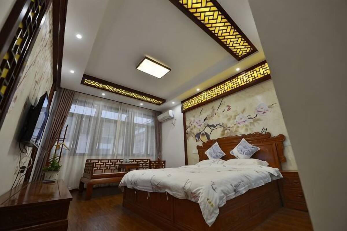 A bedroom with a wooden bed, a bench, a TV, and a decorative wall.