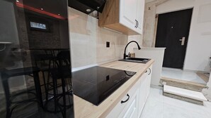 Een moderne keuken met een zwart inductiekookveld, witte kastjes en een houten aanrecht.