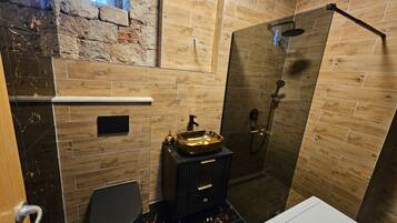 Een badkamer met douche, toilet en wastafel.