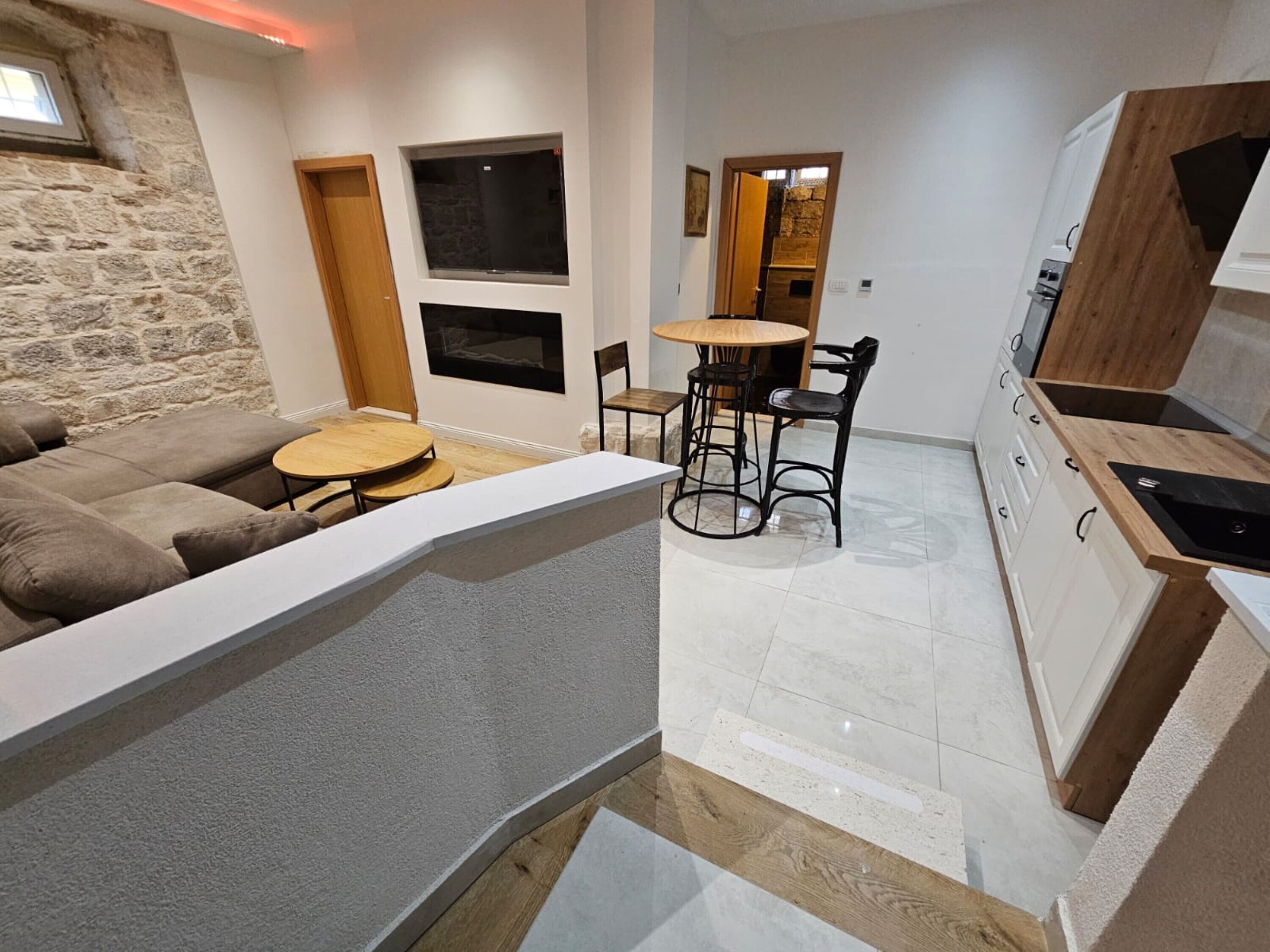 Una sala moderna con un sofá, una mesa redonda y una zona de cocina con armarios y una encimera.