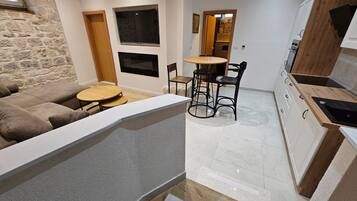 Una sala moderna con un sofá, una mesa redonda y una zona de cocina con armarios y una encimera.