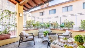 A patio with outdoor seating, potted plants, and a table set for dining.