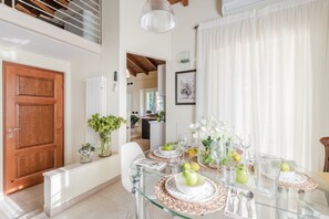 A dining area with a glass table, white chairs, and a wooden door. - San Concordio Terrace (Lucca)