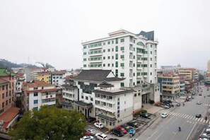 A multi-story building with a flat roof and a mix of architectural styles, surrounded by other buildings and a busy street.