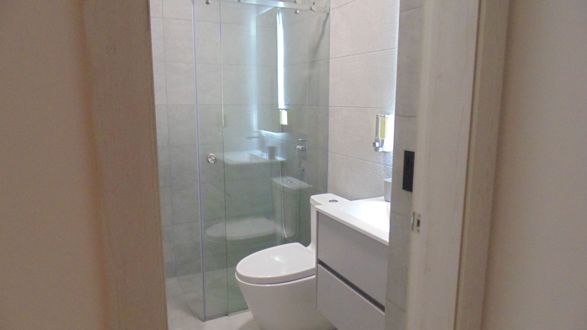 A modern bathroom with a glass-enclosed shower, a toilet, and a sink.