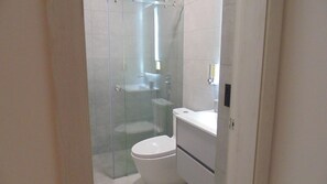 Un baño moderno con cabina de ducha de vidrio, inodoro y lavabo.