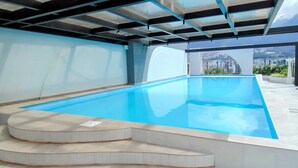 Piscina interior com vista clara para o horizonte urbano através de grandes janelas.