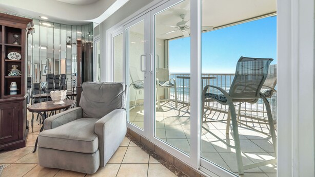 A balcony with a chair and a table, a ceiling fan, and a view of the ocean. - Beachfront Bliss! Spacious 1,800 Sq ft 3BR Sleeps 12 - Oceans 9D - Gulfshores  (Gulf Shores)