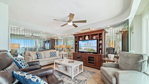 A modern living room with a television, leather sofas, and a wooden entertainment center. - Beachfront Bliss! Spacious 1,800 Sq ft 3BR Sleeps 12 - Oceans 9D - Gulfshores  (Gulf Shores)