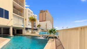 A hotel pool area with a clear blue pool, a wooden deck, and a white fence. - Beachfront Bliss! Spacious 1,800 Sq ft 3BR Sleeps 12 - Oceans 9D - Gulfshores  (Gulf Shores)