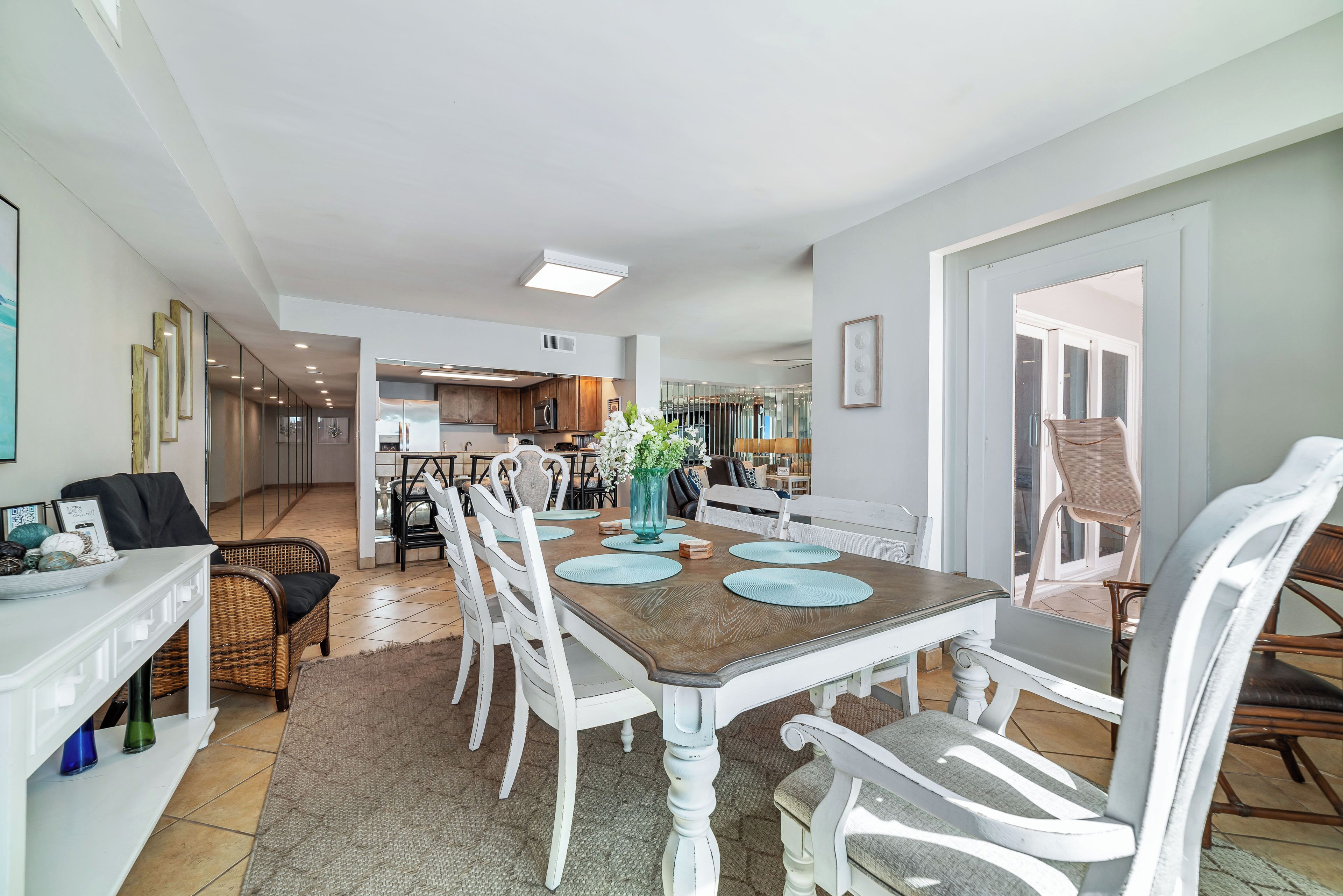 A dining area with a wooden table, white chairs, and a vase with flowers.