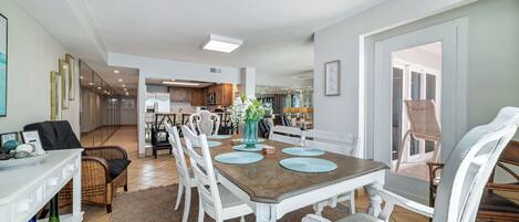 A dining area with a wooden table, white chairs, and a vase with flowers.