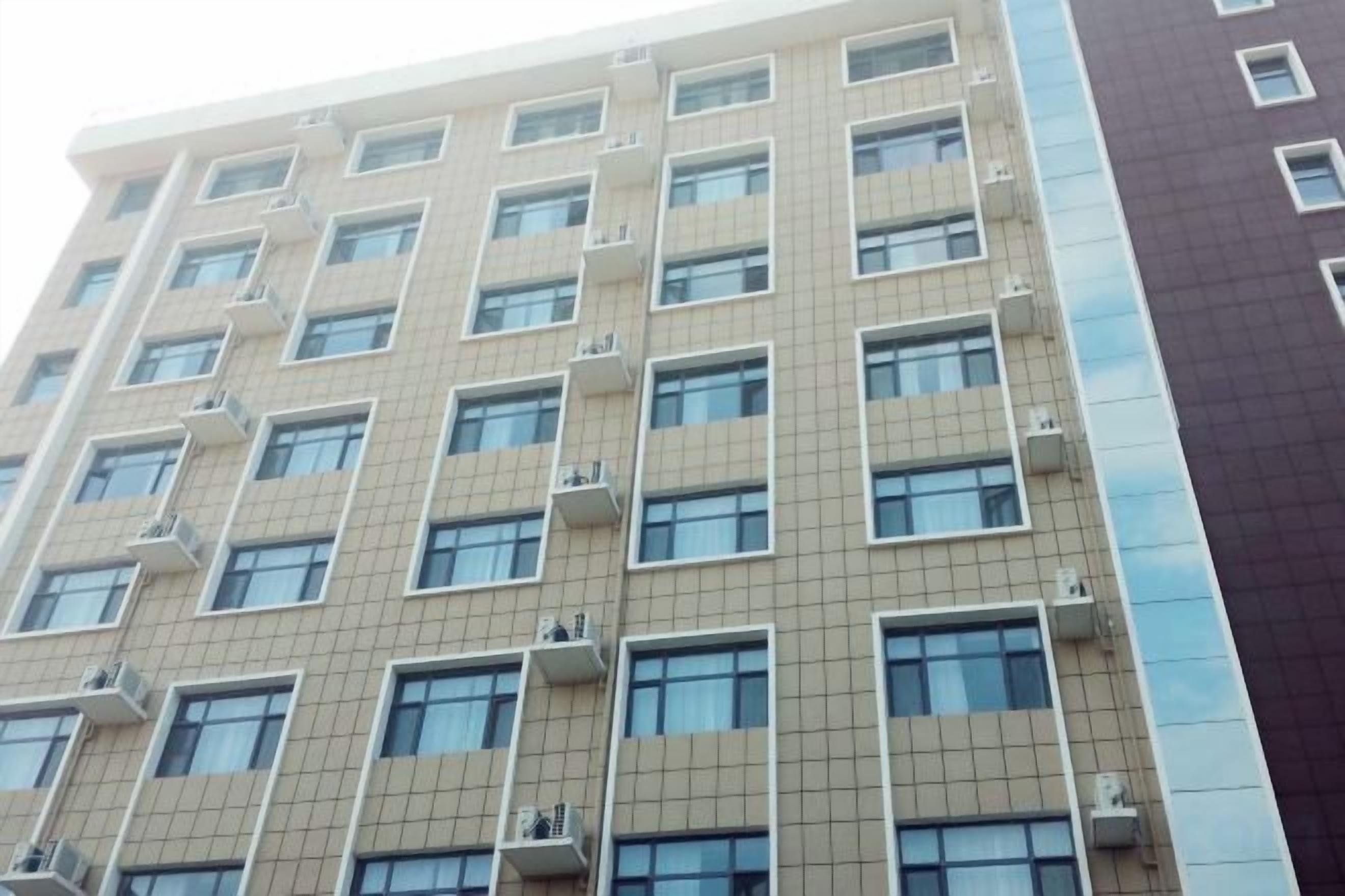A multi-story building with a grid of windows and air conditioning units.