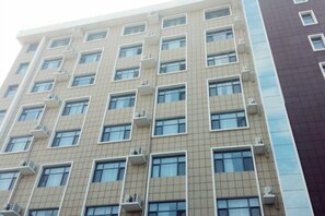 Un edificio de varios pisos con una fachada de ventanas y unidades de aire acondicionado.