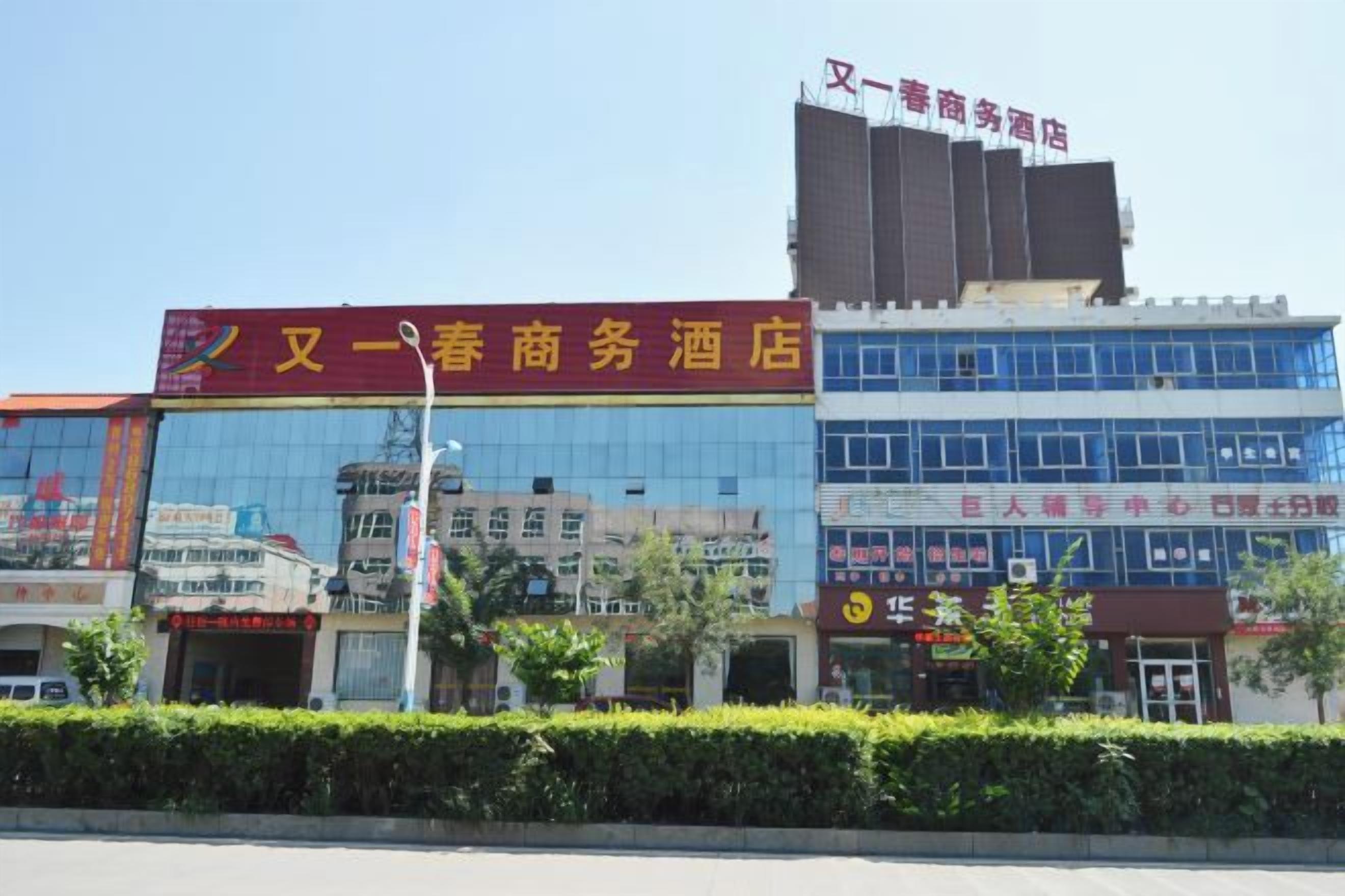 A hotel with a red sign, a glass facade, and a clear sky.