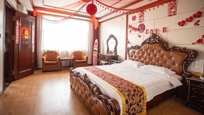 A bedroom with a large bed, two chairs, a dresser, and a mirror. - Youyichun Business Hotel (Zhao County)