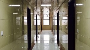 A long, narrow hallway with reflective floors and walls, leading to a door at the end. - Youyichun Business Hotel (Zhao County)