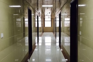 A long, narrow hallway with reflective floors and walls, leading to a door at the end. - Youyichun Business Hotel (Zhao County)