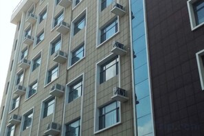 A multi-story building with a modern architectural design, featuring a series of windows and air conditioning units. - Youyichun Business Hotel (Zhao County)