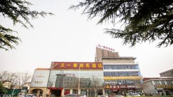 Een meerlaags gebouw met borden die een hotel en commerciële ruimtes op de begane grond aangeven.
