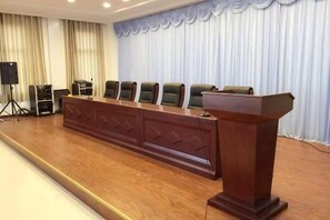 Una sala de conferencias con una larga mesa de madera, varias sillas y un atril.