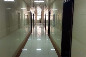 A long, narrow hallway with reflective floors and doors on both sides. - Youyichun Business Hotel (Zhao County)