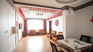 A spacious living area with a dining table, sofas, and a red decorative ceiling. - Youyichun Business Hotel (Zhao County)