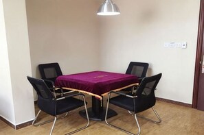 Una habitación pequeña con una mesa y cuatro sillas, una lámpara colgante y una puerta.