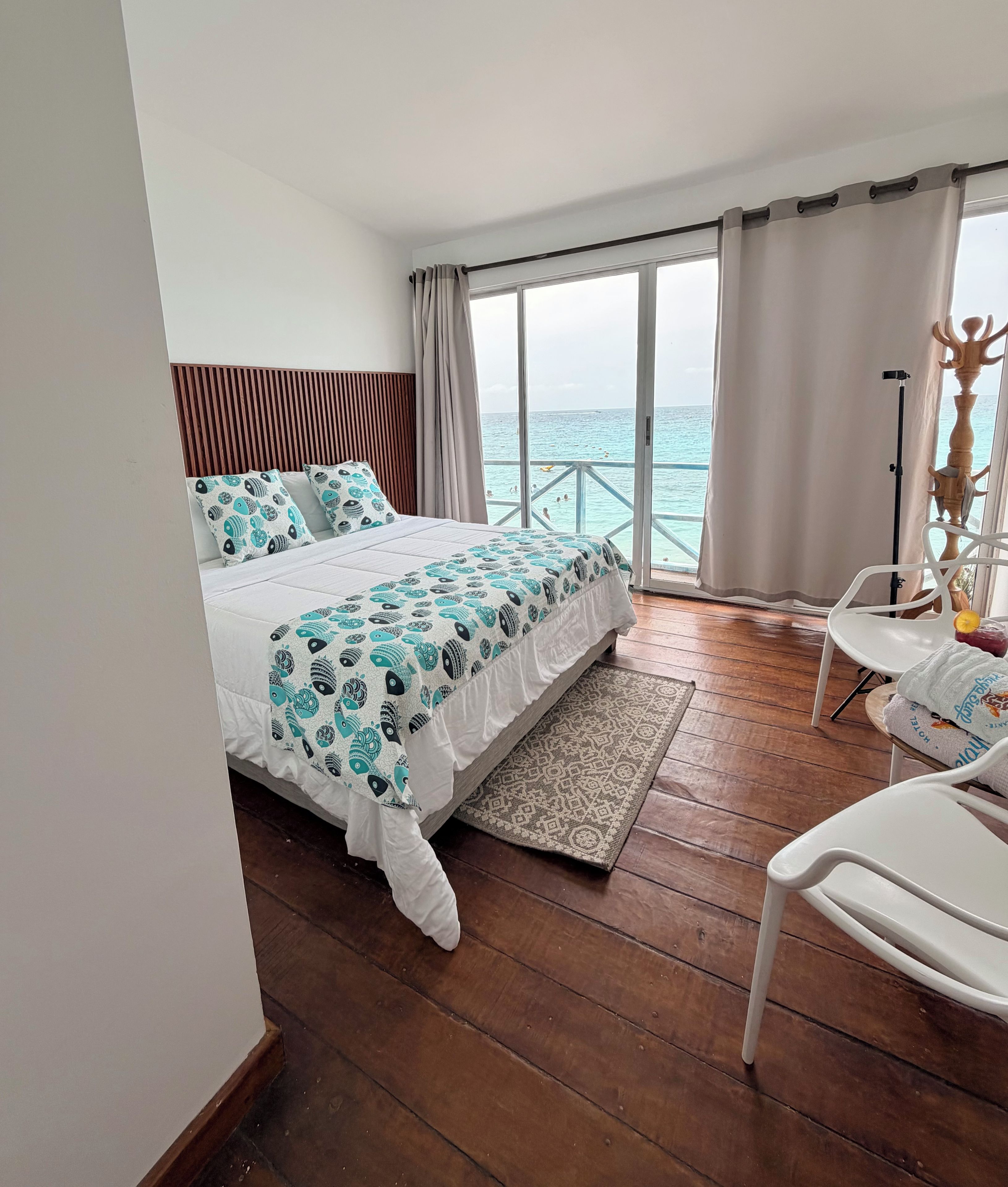 Ein Hotelzimmer mit Bett, Meerblick, Balkon und Stuhl.
