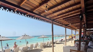 A beachside café with wooden furniture, umbrellas, and a view of the beach. - HOTEL PLAYA SURF BARÚ (Cartagena)