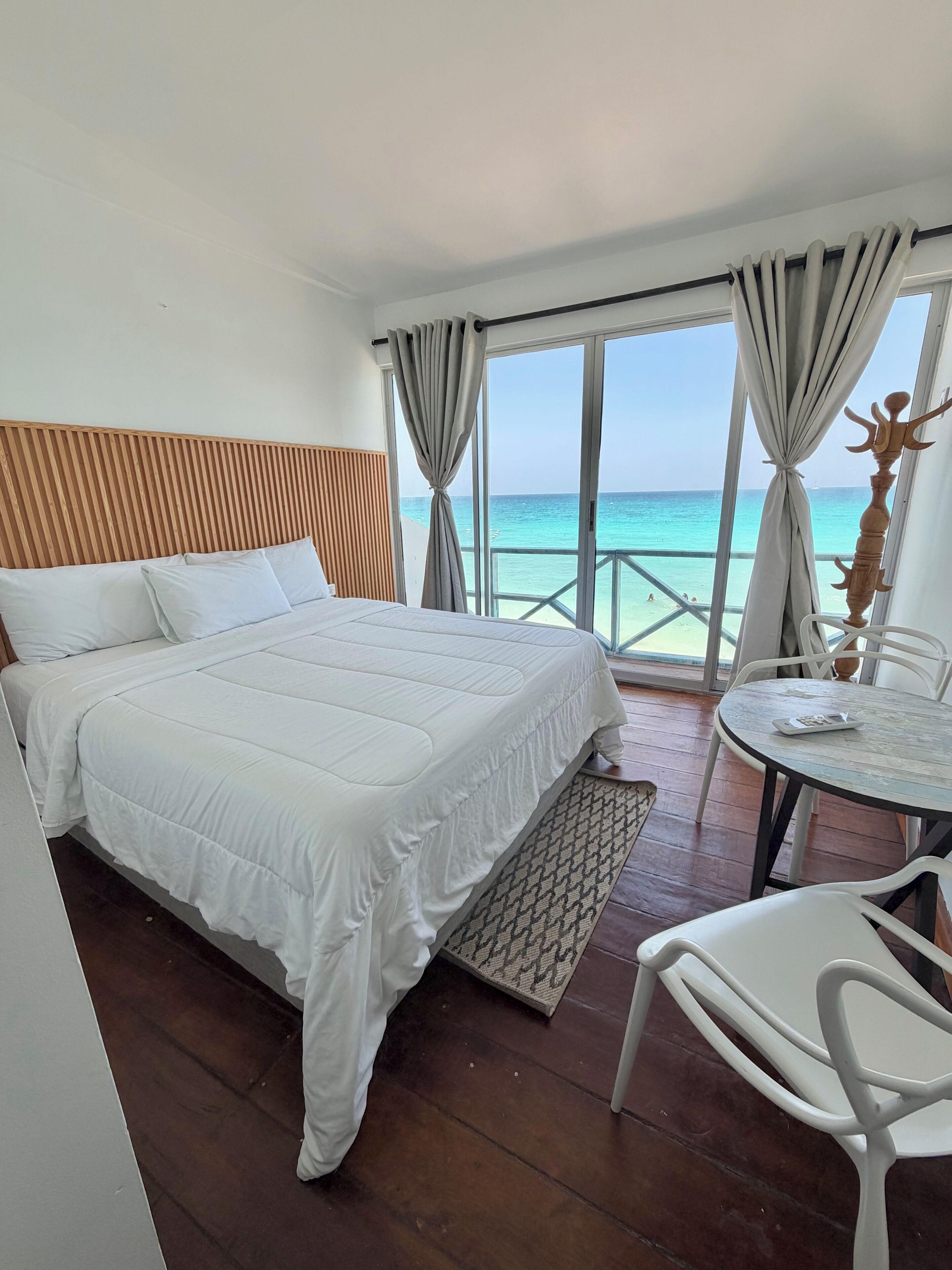Een hotelkamer met een bed, een kleintje tafeltje en uitzicht op het strand.