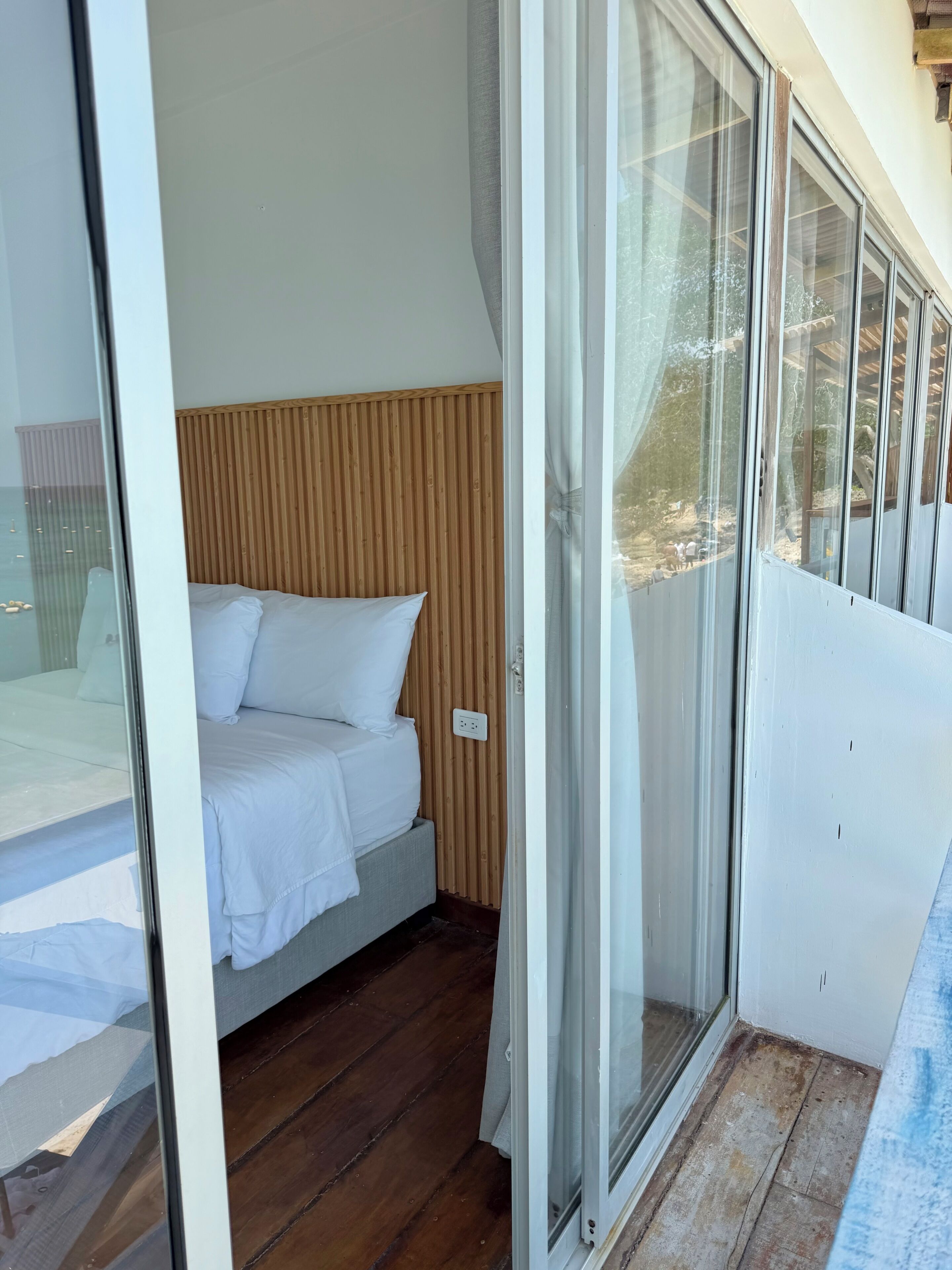 Ein Schlafzimmer mit einem Bett, einem Holzkopfende und einer Schiebetür zu einem Außenbereich.