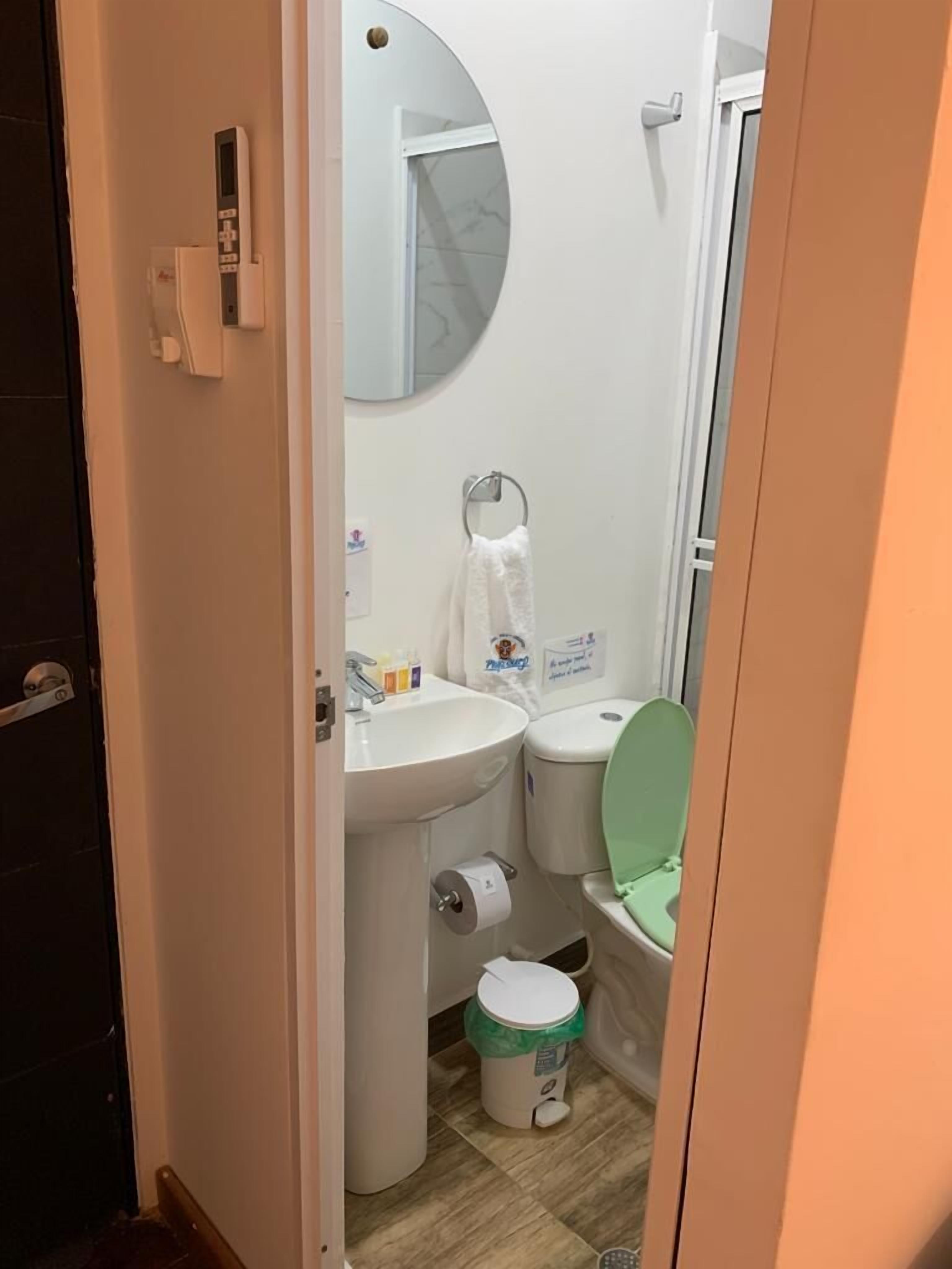 A small, compact bathroom with a toilet, sink, and mirror.