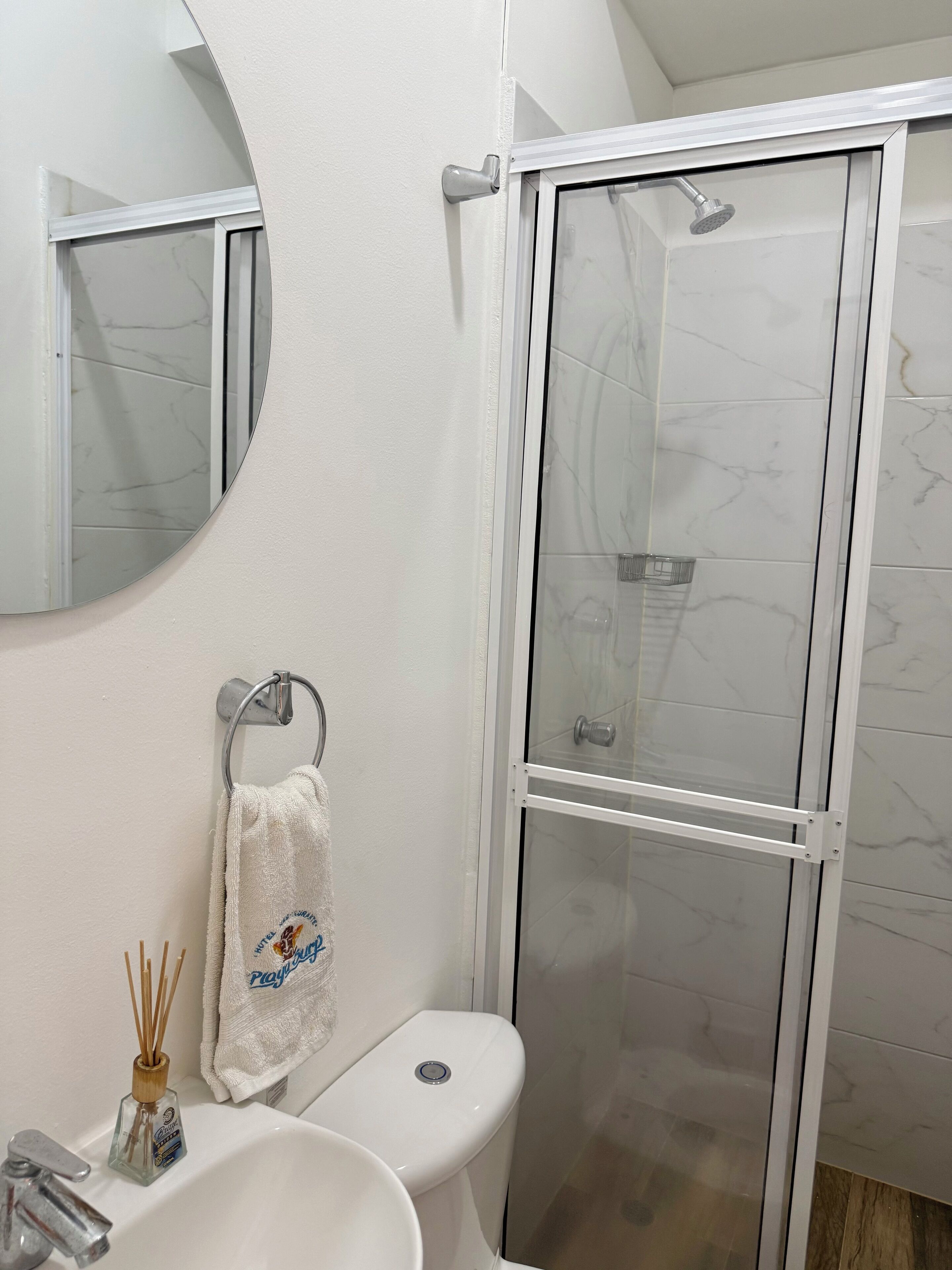 A bathroom with a white sink, toilet, and a glass-enclosed shower.