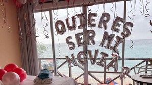A bedroom with a bed, a table, and chairs. There are balloons and a message in Spanish. - HOTEL PLAYA SURF BARÚ (Cartagena)
