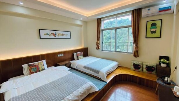 A hotel room with two beds, a window with curtains, a wooden bench, and a small table with a plant. - FenYangJu Hotel (Longmen)