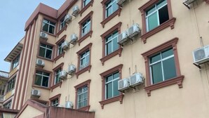 A multi-story building with air conditioning units attached to the exterior of each window. - FenYangJu Hotel (Longmen)