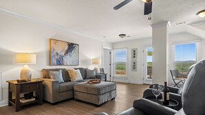 A modern living room with a sectional sofa, a coffee table, and a dining area with a chair and table. - The Overlook - best views on the lake!  (Hot Springs)