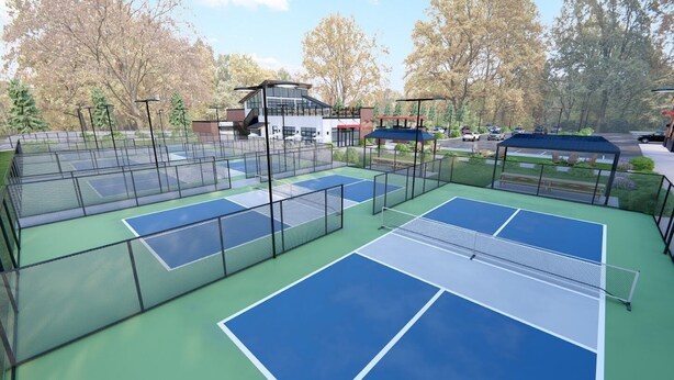 An outdoor tennis court with multiple courts, a covered seating area, and a building in the background.