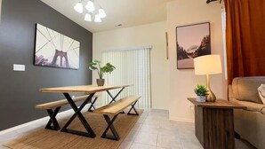 A modern living room with a wooden dining table, benches, a sofa, and a side table with a lamp.