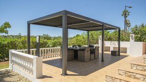 Un patio exterior con pérgola, mobiliario de mimbre y una mesa lista para comer.