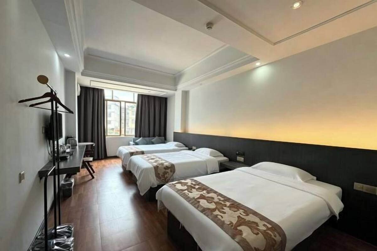 A hotel room with two beds, a desk, a chair, a TV, and a window with curtains.
