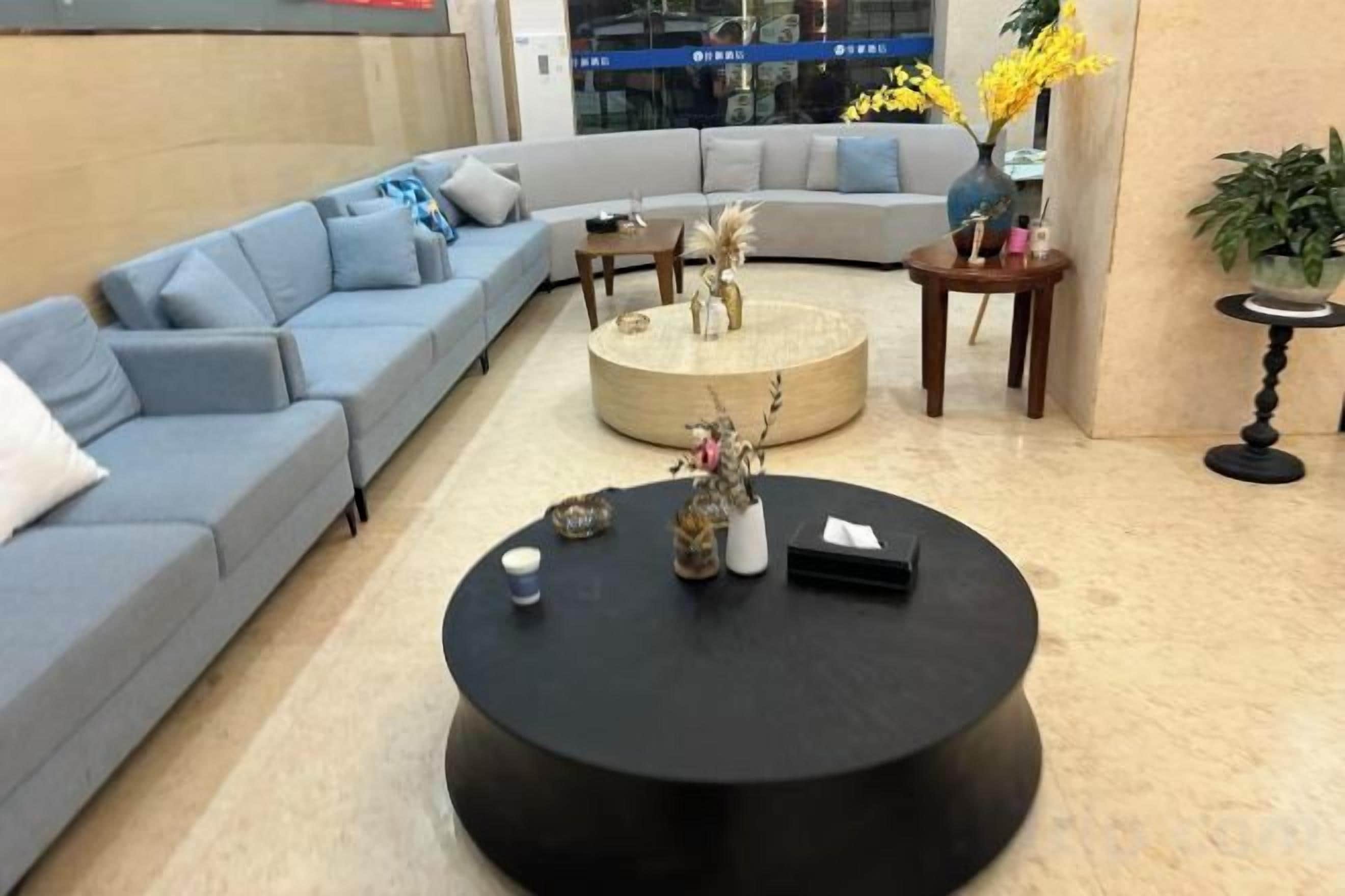 A modern living room with a sectional sofa, a round coffee table, and a vase with flowers.