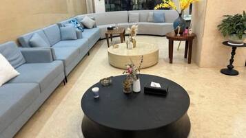 A modern living room with a sectional sofa, a round coffee table, and a vase with flowers.
