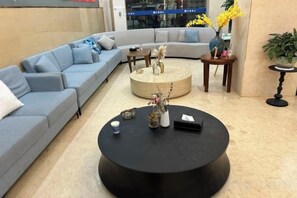 Een moderne woonkamer met een modulaire bank, een ronde salontafel en een vaas met bloemen.