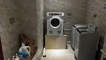 A laundry room with a washing machine, dryer, and a drying rack.