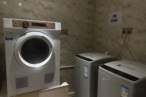 A laundry room with a front-loading washing machine and a stacked dryer. - Bobai Lingli Hotel (Bobai Bus Terminal) (Bobai)