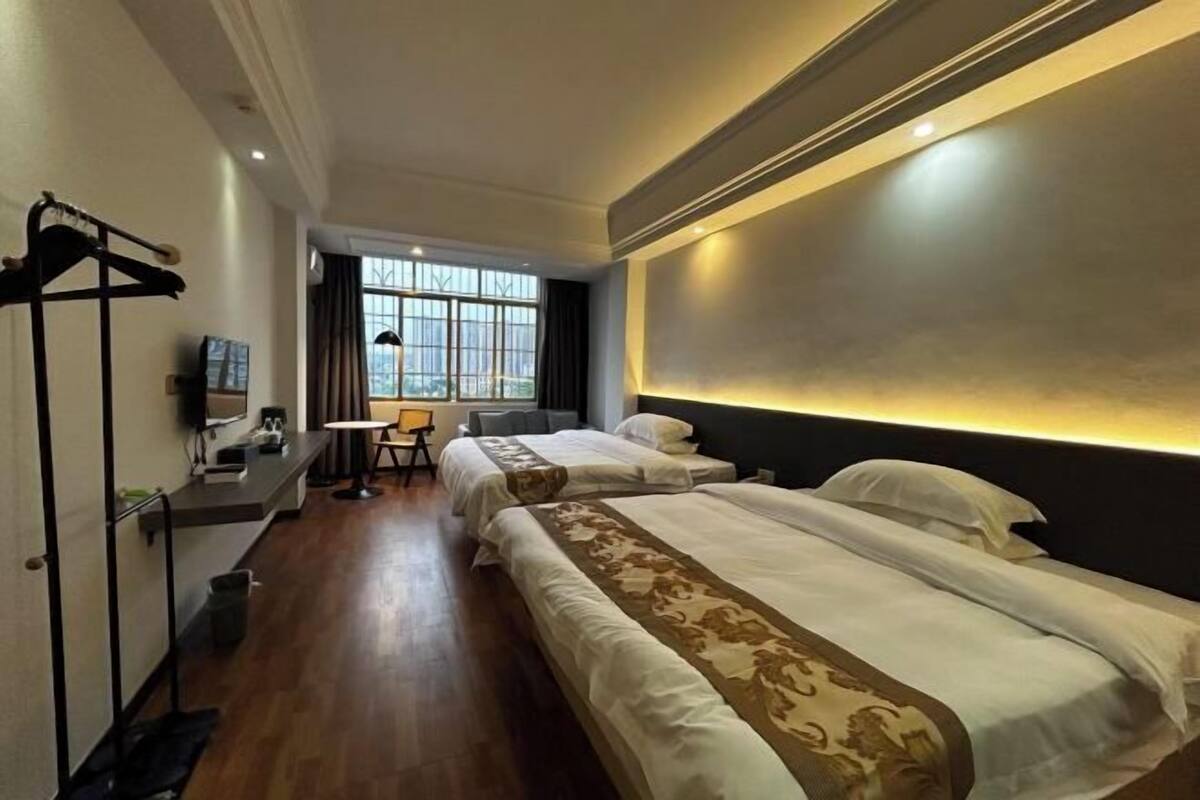 A hotel room with two beds, a desk, a chair, and a window with curtains.