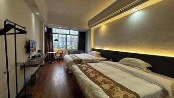 A hotel room with two beds, a desk, a chair, and a window with curtains.