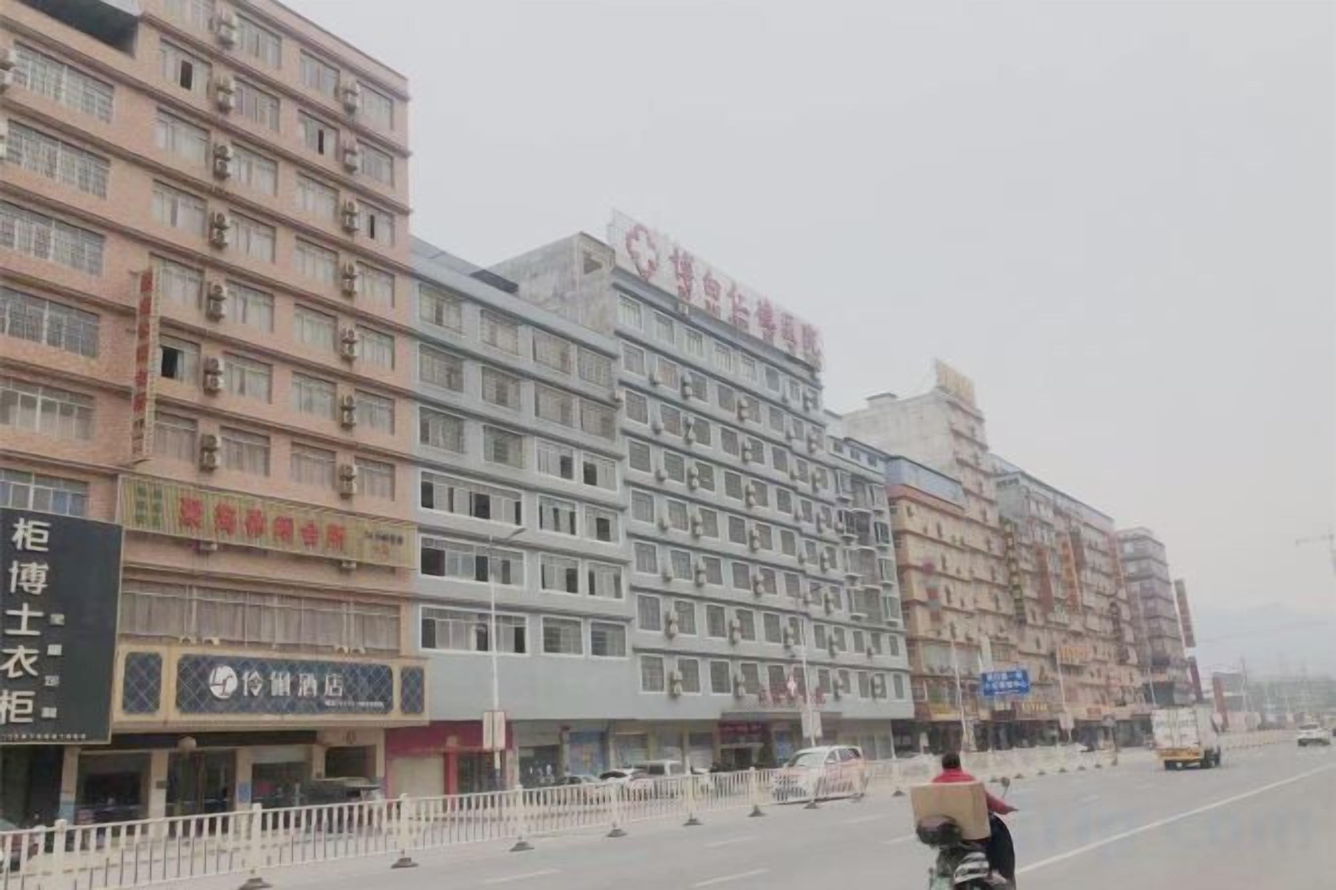 A multi-story building with commercial establishments on the ground floor, including a visible signboard.